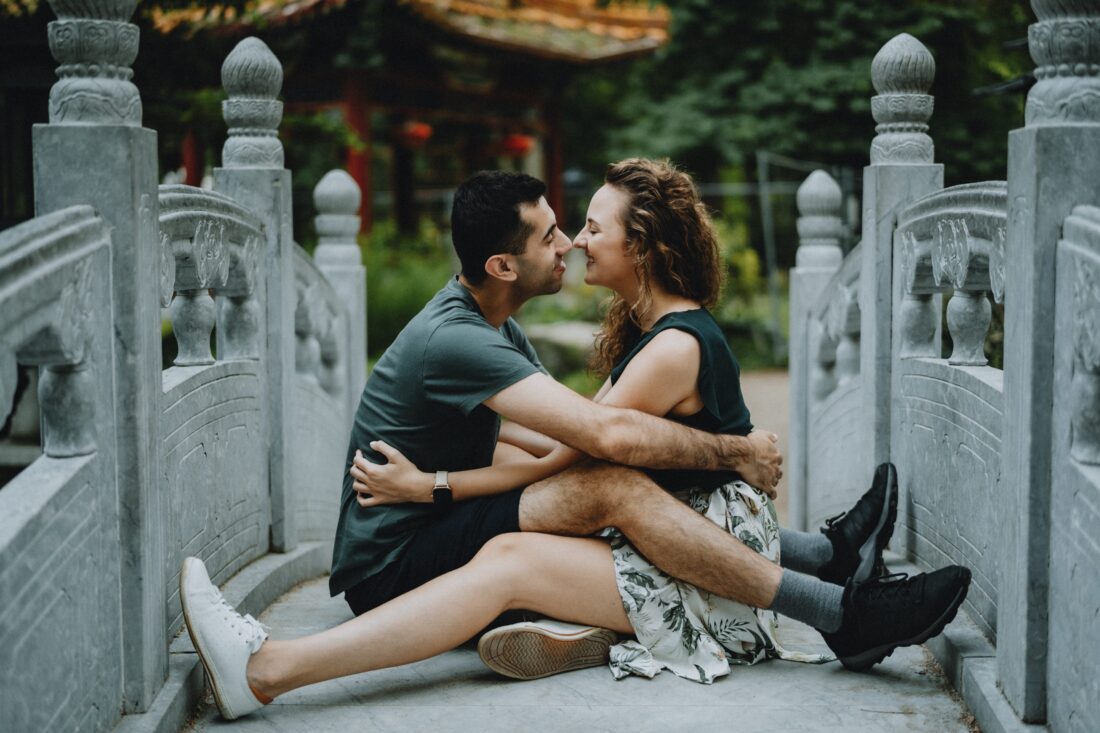 a man and woman sitting on a bridge kissing